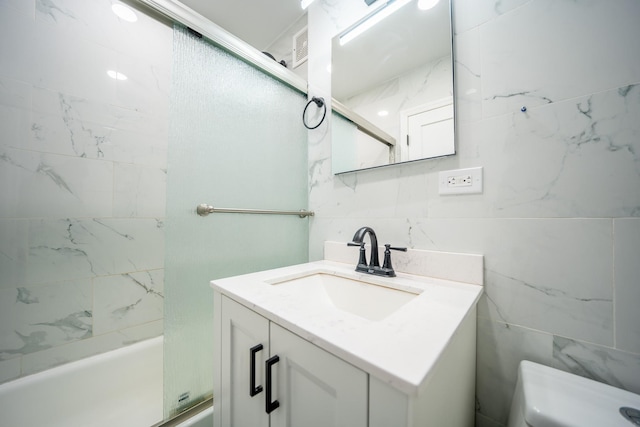 bathroom with tile walls, vanity, toilet, and shower / bathtub combination