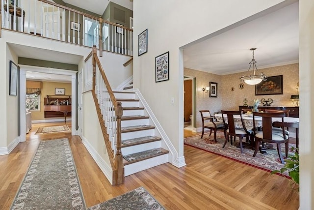 stairs featuring baseboards, wood finished floors, and wallpapered walls