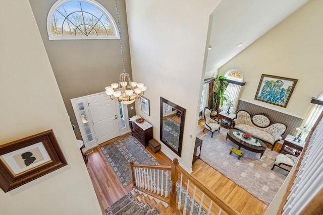 entryway with an inviting chandelier, wood finished floors, a wealth of natural light, and high vaulted ceiling