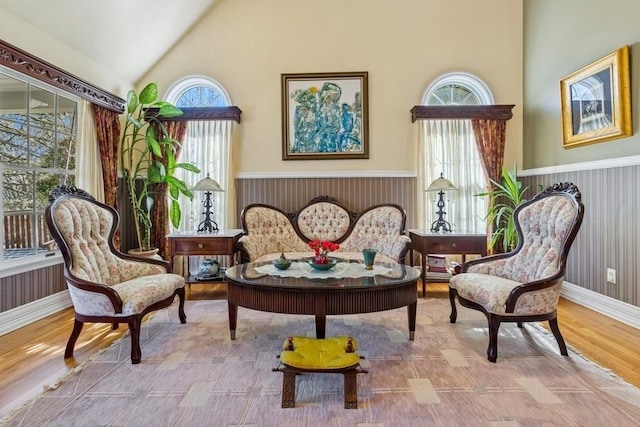 living area featuring high vaulted ceiling, baseboards, and wood finished floors