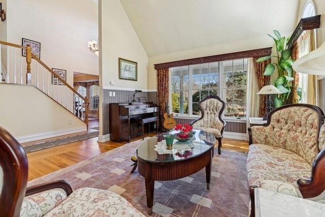 living room featuring stairway, wood finished floors, baseboards, and high vaulted ceiling