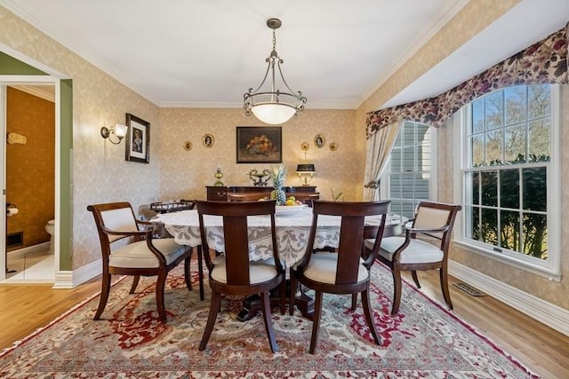 dining space with wallpapered walls, wood finished floors, and baseboards