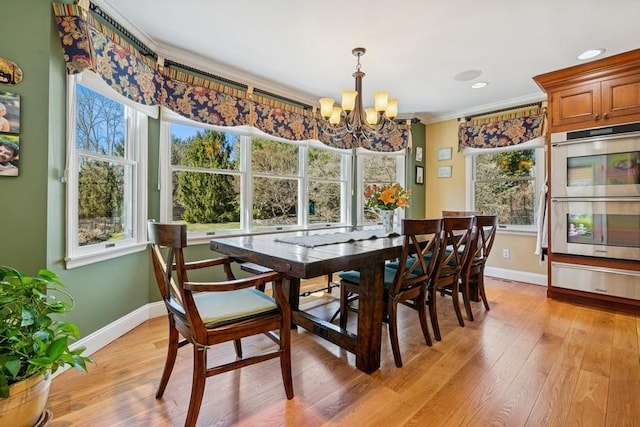 dining room featuring an inviting chandelier, crown molding, baseboards, and light wood finished floors