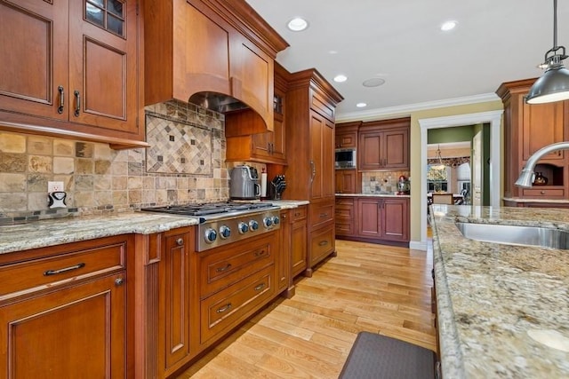 kitchen with light wood-type flooring, a sink, backsplash, stainless steel appliances, and crown molding