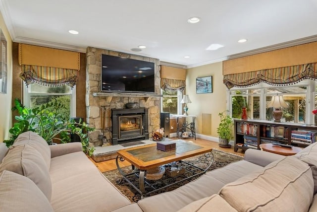 living room featuring plenty of natural light, a stone fireplace, wood finished floors, and crown molding