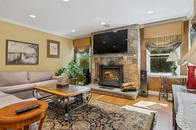 living room featuring wood finished floors, baseboards, recessed lighting, a stone fireplace, and crown molding