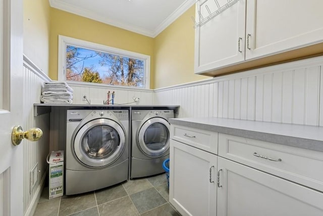 clothes washing area featuring cabinet space, wainscoting, crown molding, and washing machine and clothes dryer