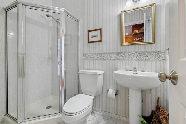 full bathroom with a shower stall, wallpapered walls, a wainscoted wall, toilet, and tile patterned floors