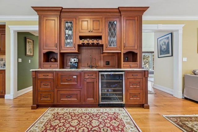 bar with ornamental molding, a sink, wine cooler, light wood finished floors, and indoor wet bar