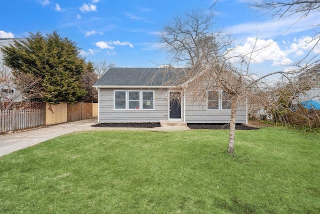 view of front facade with driveway, fence, and a front yard