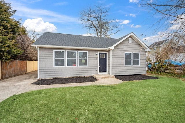 view of front of property featuring a shingled roof, fence, and a front lawn