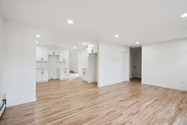 unfurnished living room with baseboards, baseboard heating, light wood-style flooring, and recessed lighting