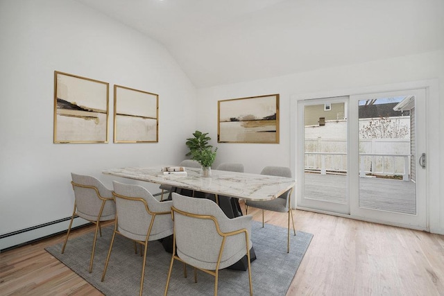 dining room featuring light wood finished floors and vaulted ceiling