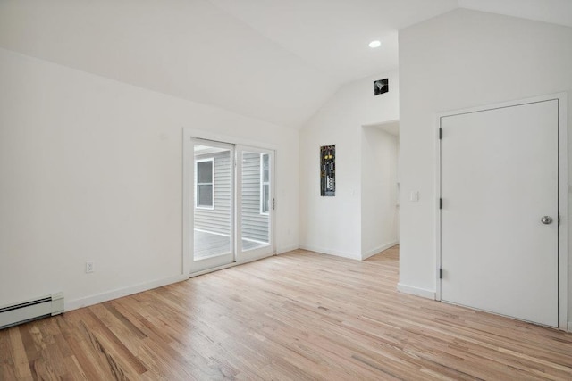 empty room featuring lofted ceiling, light wood-style floors, baseboards, and a baseboard heating unit