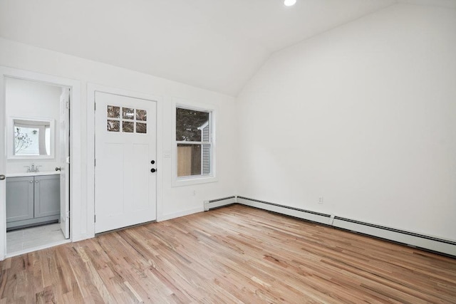 foyer with lofted ceiling, a baseboard heating unit, and light wood finished floors