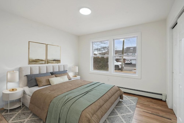 bedroom with baseboard heating and wood finished floors