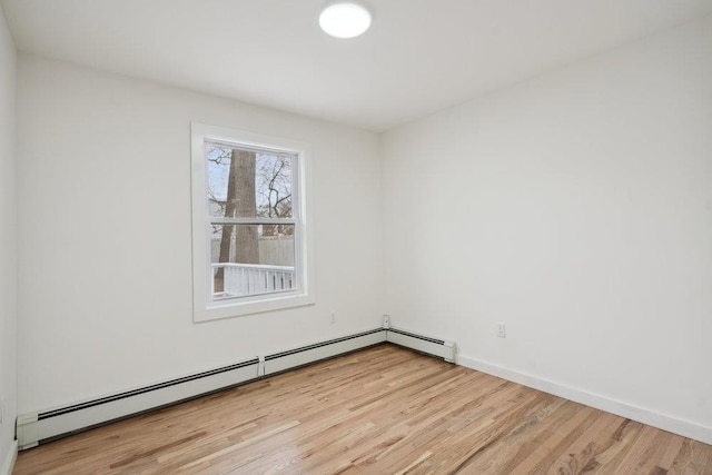 unfurnished room featuring light wood finished floors, baseboard heating, and baseboards