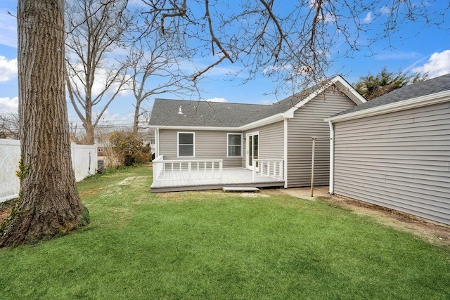 back of house featuring fence, a deck, and a lawn