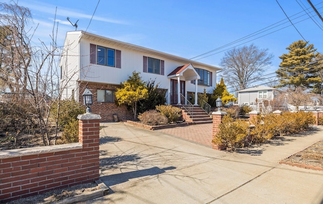 bi-level home featuring brick siding, driveway, and fence