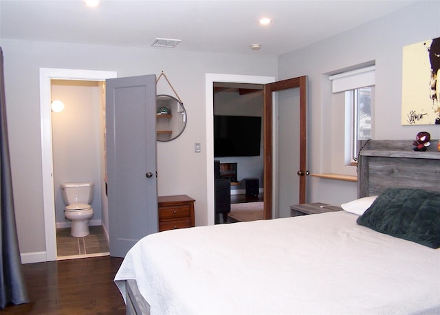 bedroom featuring dark wood-style flooring, recessed lighting, visible vents, ensuite bathroom, and baseboards