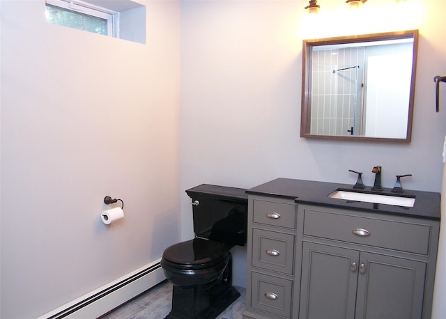 bathroom featuring wood finished floors, baseboard heating, vanity, and toilet