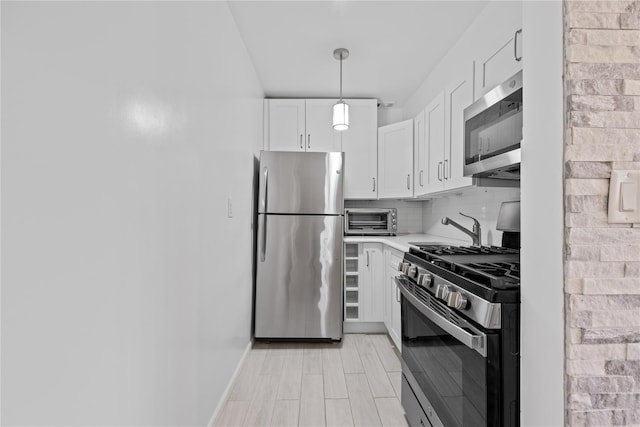 kitchen featuring a toaster, stainless steel appliances, light countertops, decorative backsplash, and white cabinetry