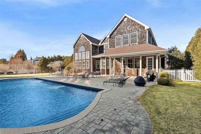 rear view of house with a patio area, fence, a fenced in pool, and a yard