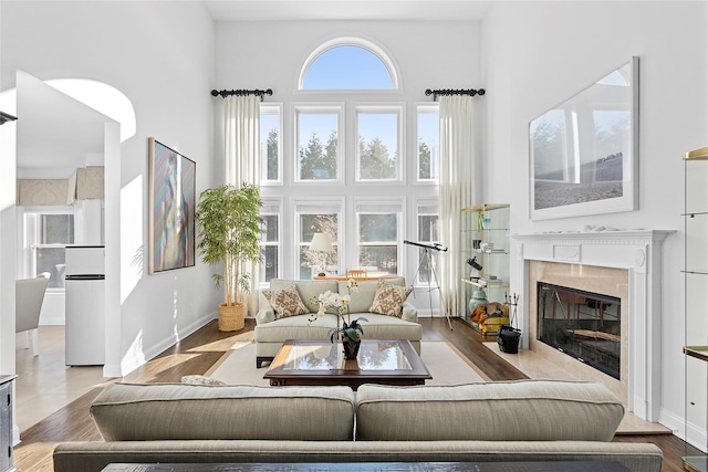 living area with baseboards, a fireplace, and a high ceiling