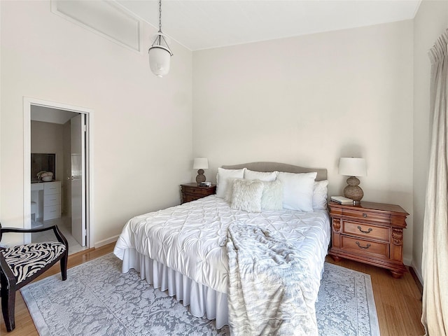 bedroom featuring wood finished floors, ensuite bath, and baseboards