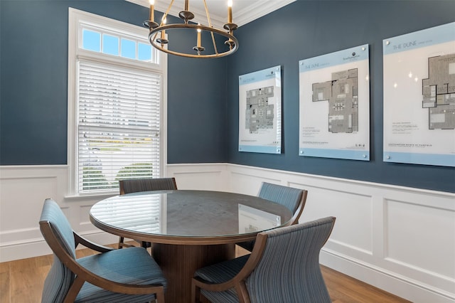 dining room with a wainscoted wall, crown molding, wood finished floors, and a notable chandelier