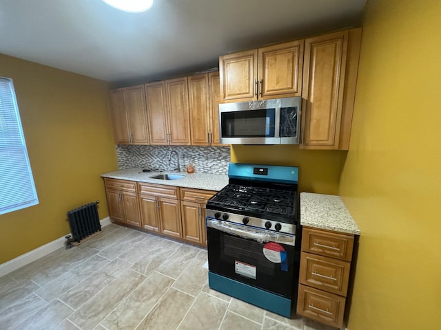 kitchen with appliances with stainless steel finishes, brown cabinets, a sink, and decorative backsplash