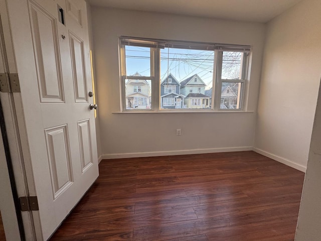 spare room with dark wood-type flooring and baseboards