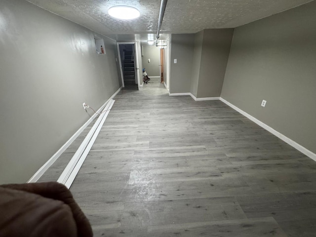 unfurnished dining area featuring stairway, a textured ceiling, baseboards, and wood finished floors