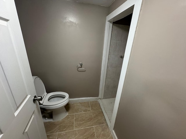 bathroom featuring a stall shower, toilet, and baseboards