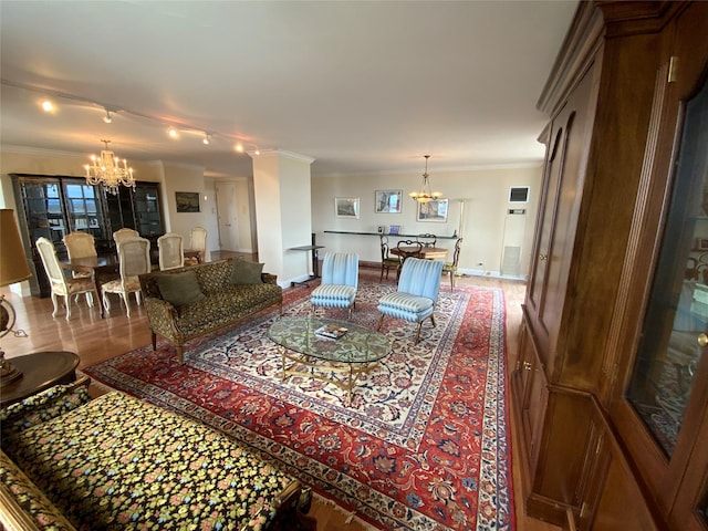 living area with a chandelier, ornamental molding, wood finished floors, and baseboards