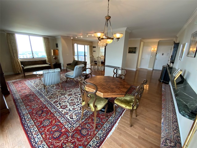 dining room with baseboards, an inviting chandelier, wood finished floors, and crown molding