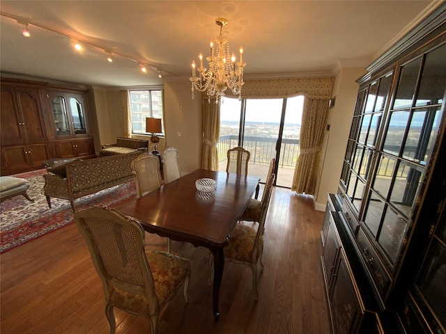 dining space with baseboards, ornamental molding, hardwood / wood-style floors, a water view, and a chandelier