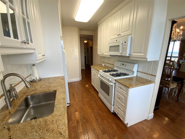 kitchen with white appliances, dark wood-style floors, white cabinets, and a sink