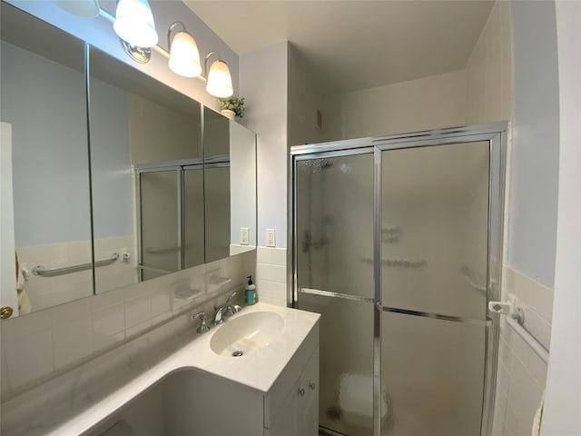 bathroom with a shower stall, vanity, and tile walls