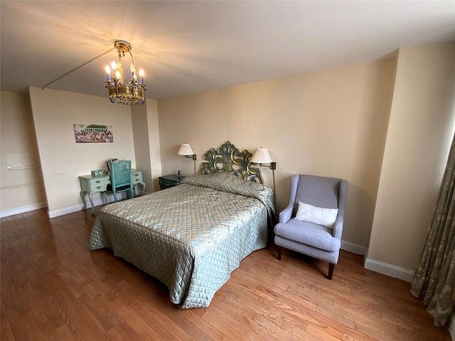 bedroom with a chandelier, hardwood / wood-style floors, and baseboards