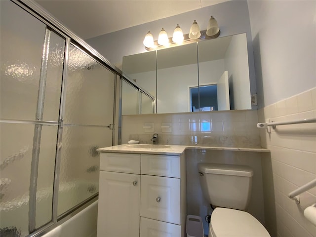 full bathroom featuring bath / shower combo with glass door, toilet, backsplash, vanity, and tile walls