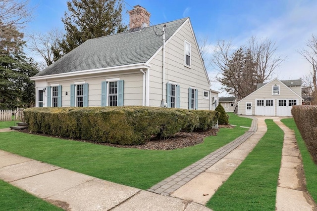 200 Village Ln, Orient, NY 11957 - view of side of home featuring an outdoor structure, a detached garage, a chimney, roof with shingles, and a yard