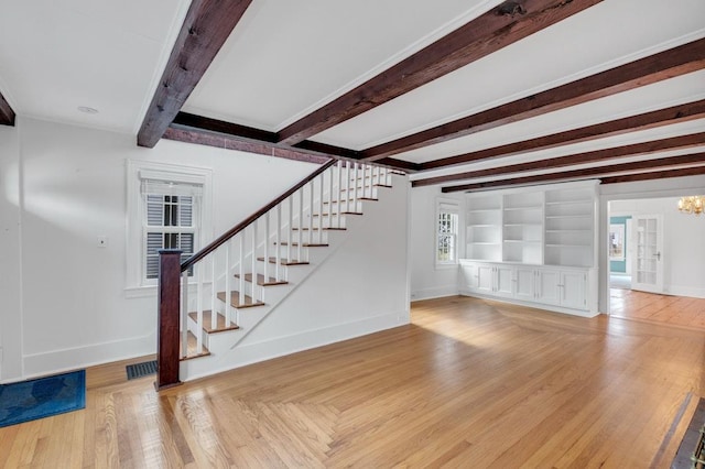 unfurnished living room with visible vents, baseboards, stairs, beamed ceiling, and wood-type flooring