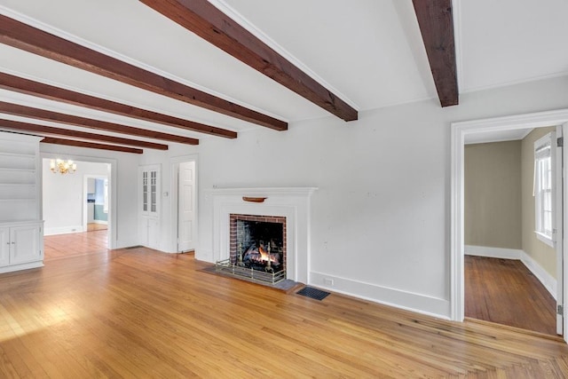 200 Village Ln, Orient, NY 11957 - unfurnished living room featuring a fireplace, a chandelier, beamed ceiling, baseboards, and light wood finished floors