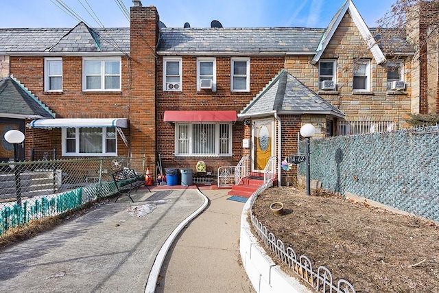 rear view of house featuring a high end roof, brick siding, fence private yard, and a chimney