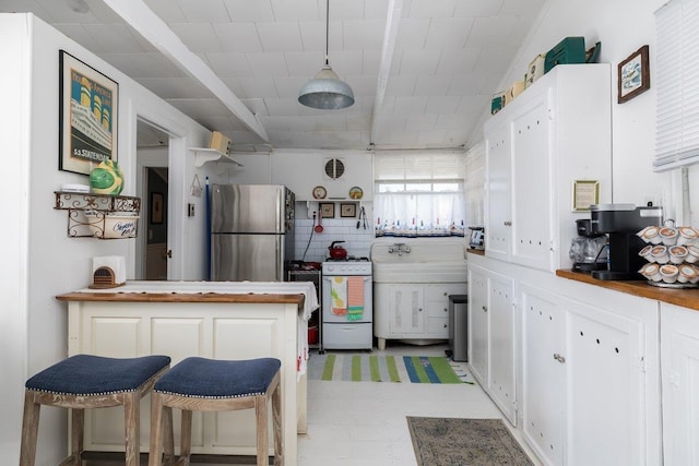 kitchen featuring white cabinets, freestanding refrigerator, a peninsula, white gas stove, and backsplash