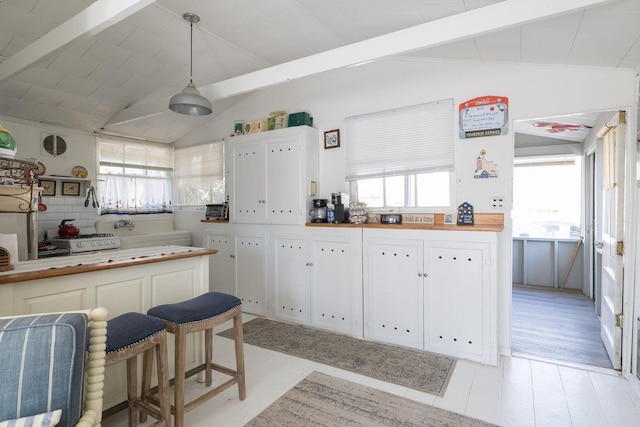 kitchen featuring vaulted ceiling with beams, white cabinets, and wooden counters