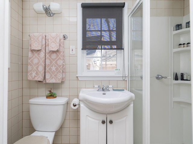 bathroom with a stall shower, vanity, toilet, and tile walls