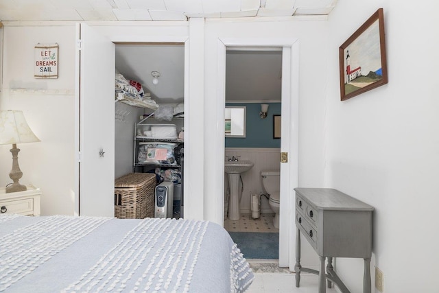 bedroom featuring a wainscoted wall, a sink, and ensuite bath