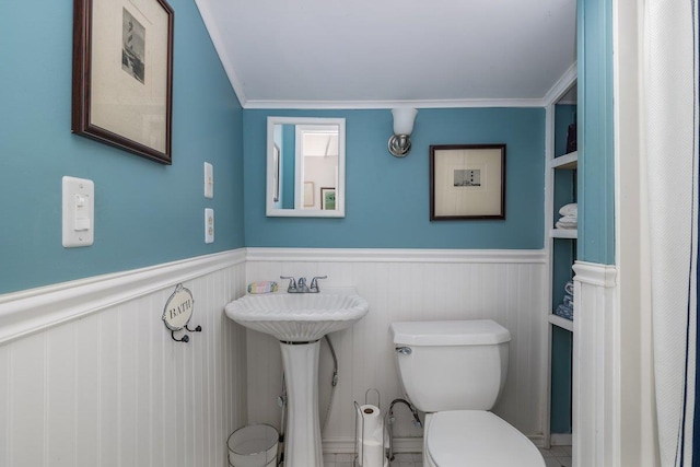 bathroom with toilet, a wainscoted wall, and ornamental molding